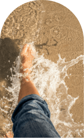 Person walking through water on beach